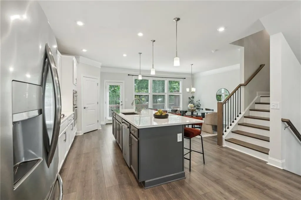 Kitchen featuring appliances with stainless steel finishes, dark wood finished floors, a kitchen island with sink, light countertops, and crown molding