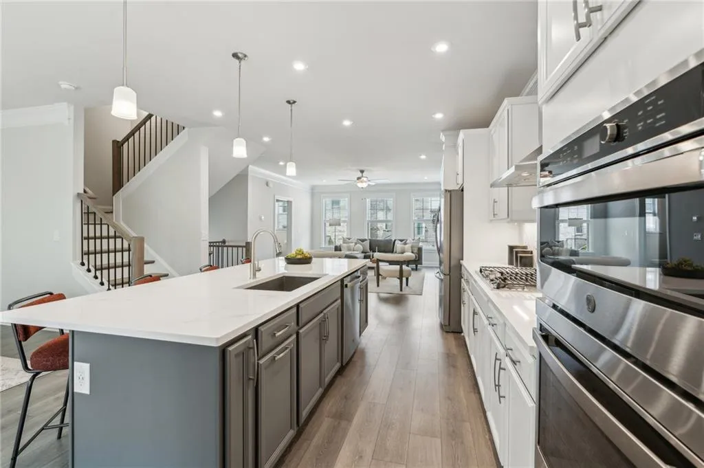 Kitchen featuring appliances with stainless steel finishes, open floor plan, gray cabinetry, ornamental molding, and a center island with sink