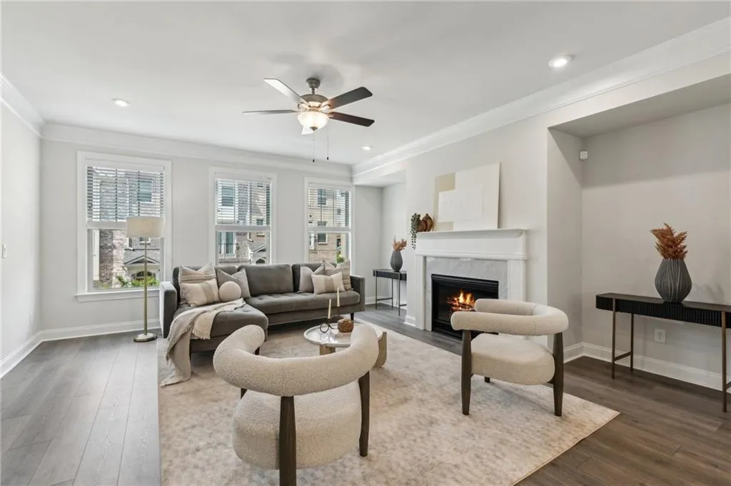 Living area featuring ornamental molding, a high end fireplace, dark wood-style flooring, a ceiling fan, and recessed lighting