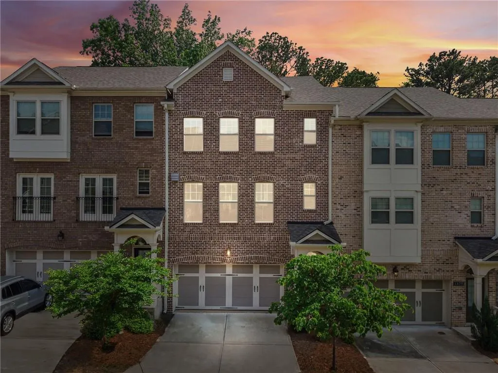 Traditional-style home featuring driveway, brick siding, an attached garage, and a shingled roof