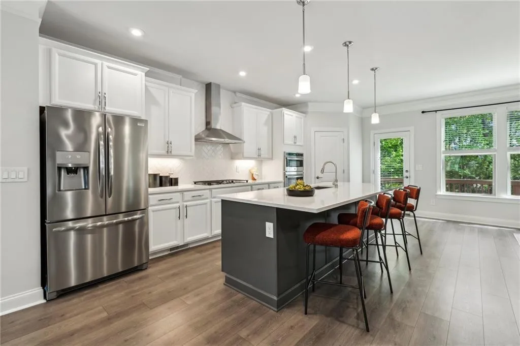 Kitchen featuring appliances with stainless steel finishes, tasteful backsplash, a center island with sink, white cabinetry, and light countertops