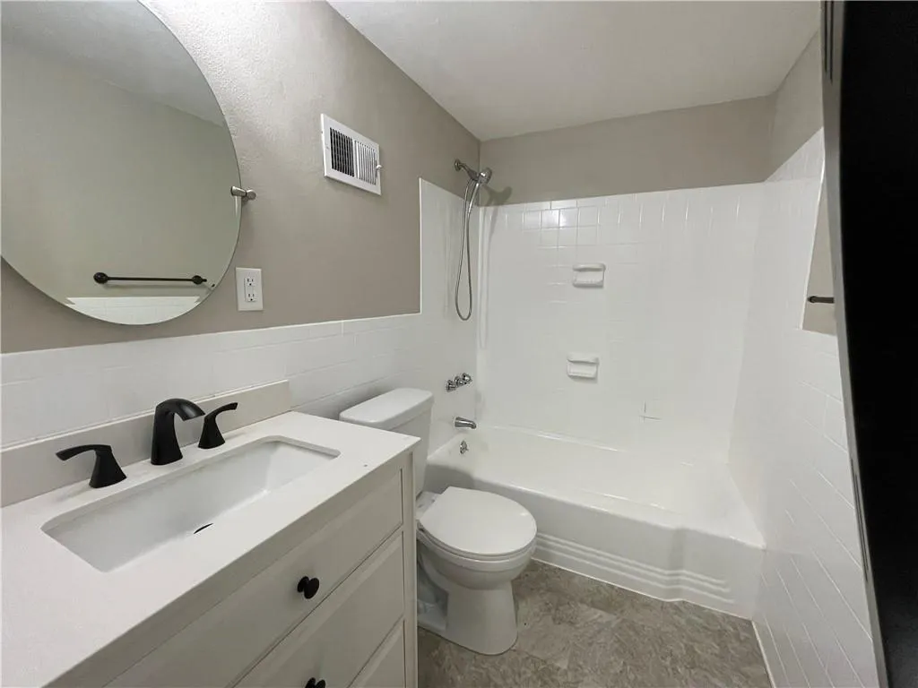 Full bathroom with bathtub / shower combination, vanity, and tile walls