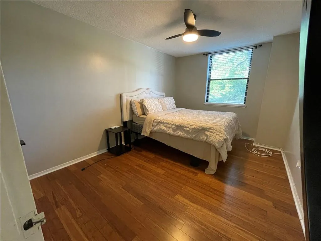 Bedroom featuring a textured ceiling, hardwood / wood-style flooring, and ceiling fan