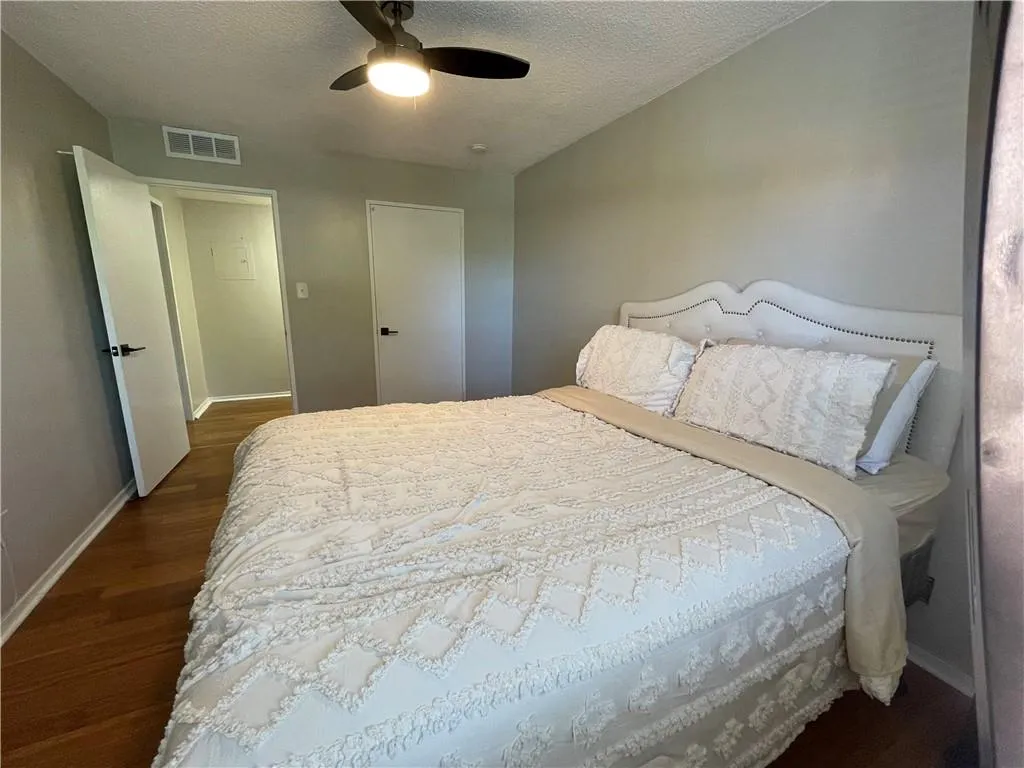 Bedroom featuring a textured ceiling, dark wood finished floors, and a ceiling fan