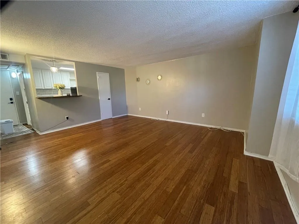 Unfurnished living room with a textured ceiling and dark wood-type flooring