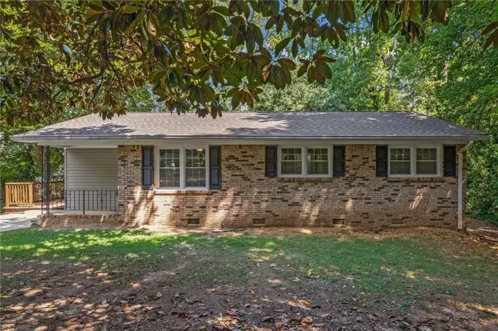 Brick exterior with dark shutters, white trim, and a shingle roof
