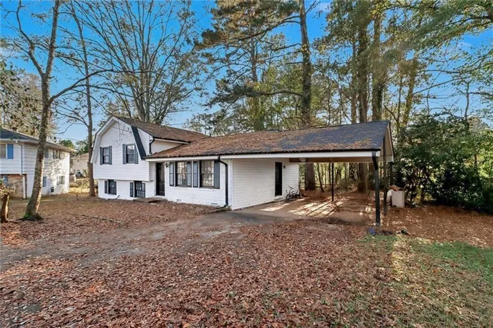 Tri-level home with brick siding, a carport, and driveway