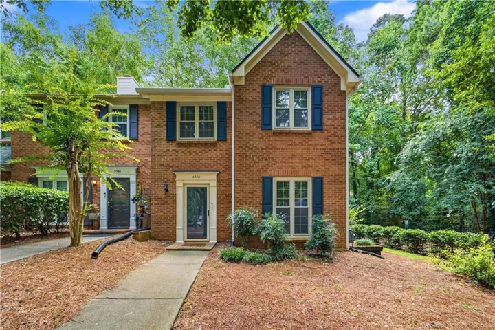 Brick exterior featuring blue window shutters and a gabled roofline