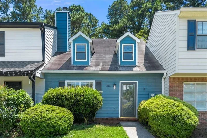Blue wood-finish siding exterior featuring a dark framed glass front door, two dormer windows, and a prominent chimney