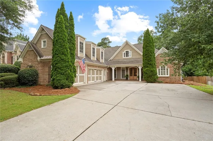 Brick and shingle exterior with decorative gables, a covered entry, multiple windows, and a multi-car garage with carriage-style doors