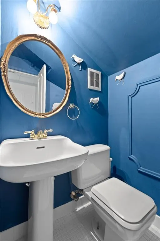 Bathroom with toilet, tile flooring, and vaulted ceiling