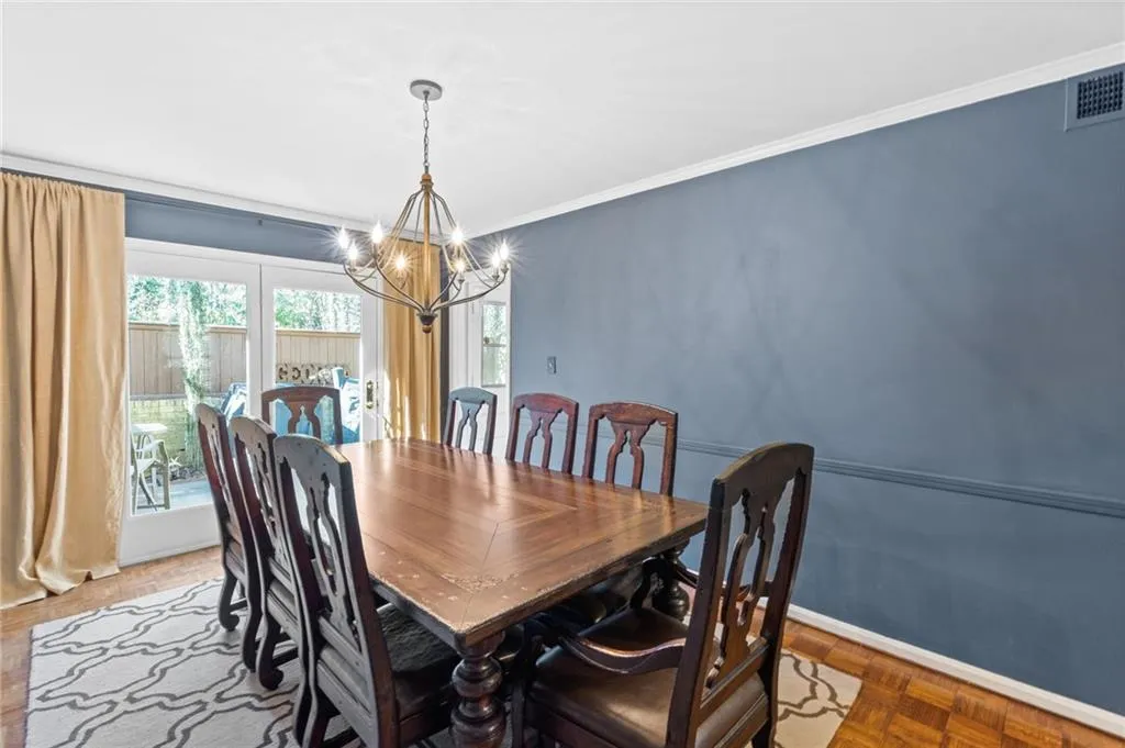 Dining area featuring an inviting chandelier, ornamental molding, and light parquet flooring