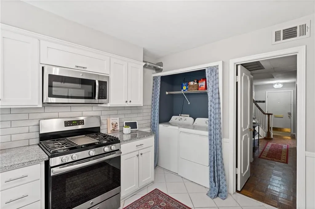 Kitchen featuring appliances with stainless steel finishes, separate washer and dryer, white cabinetry, and light parquet flooring