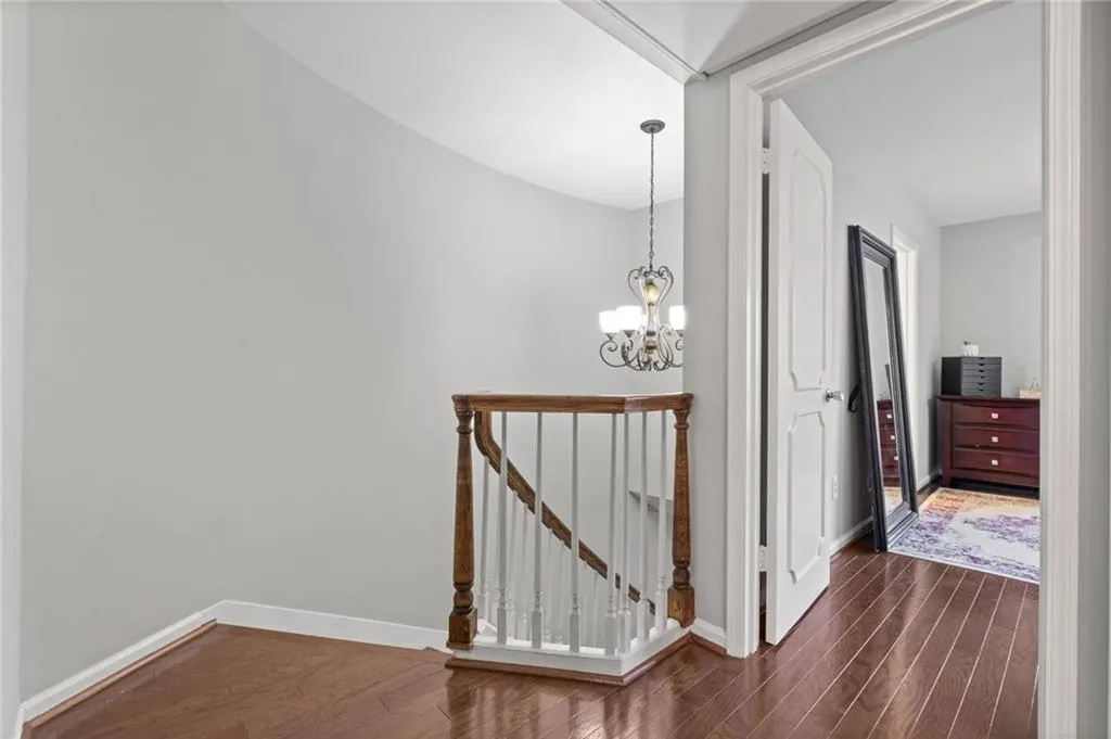 Hallway with dark hardwood / wood-style flooring and a chandelier