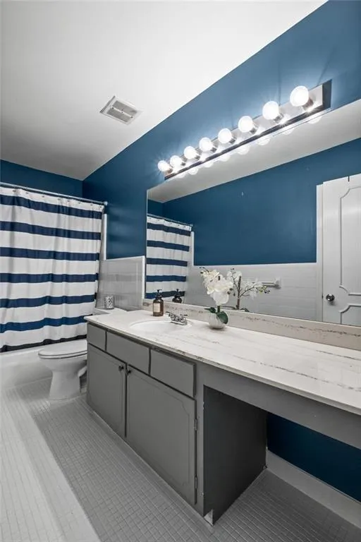 Bathroom featuring tile walls, vanity, tile flooring, and toilet
