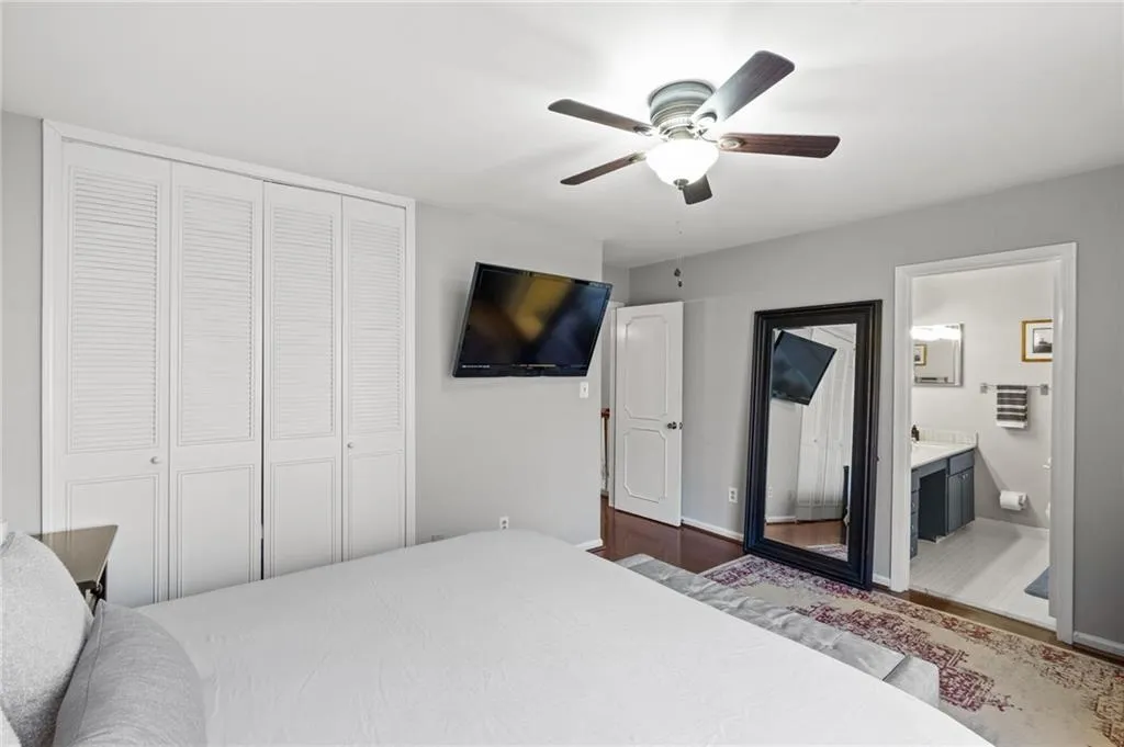 Bedroom featuring hardwood / wood-style flooring, ensuite bathroom, ceiling fan, and a closet