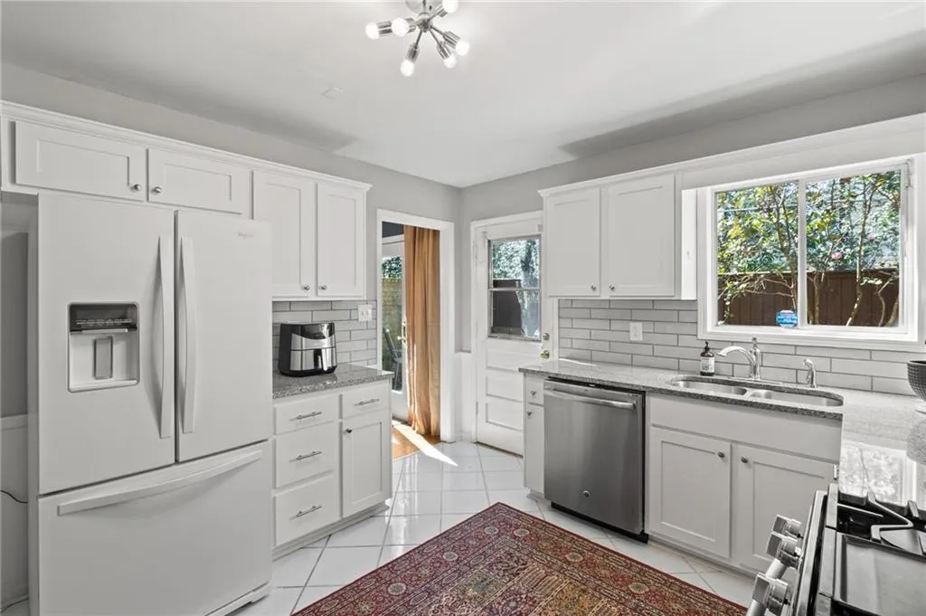 Kitchen with white fridge with ice dispenser, dishwasher, sink, and backsplash