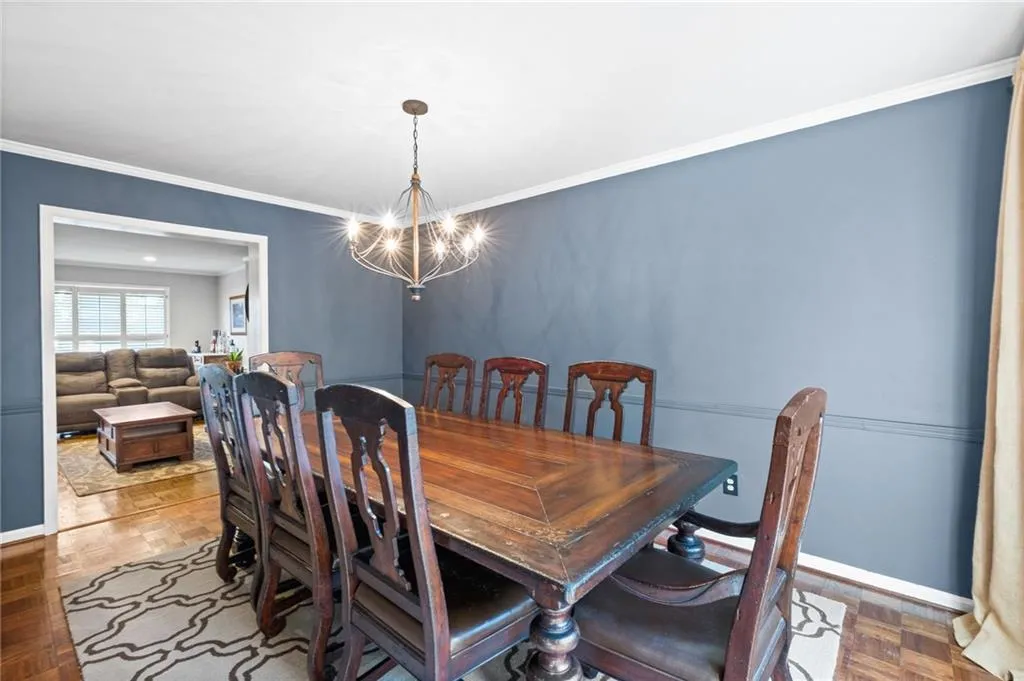 Dining area featuring an inviting chandelier, crown molding, and parquet flooring