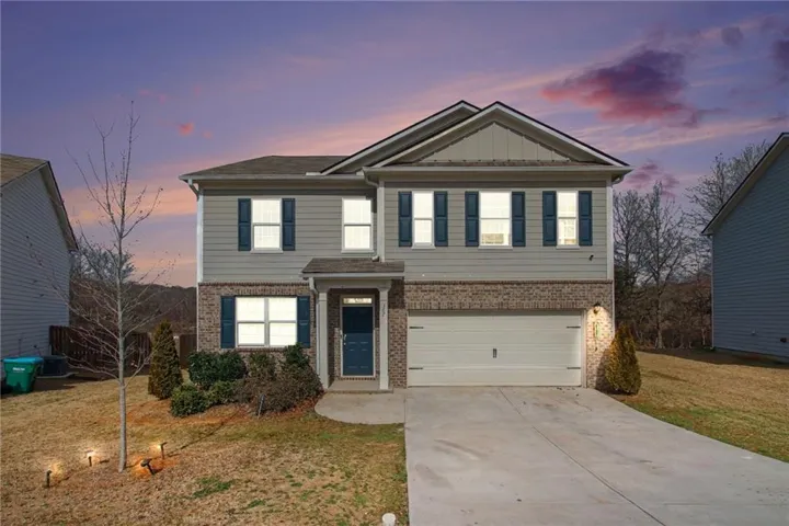View of front of home featuring brick siding, concrete driveway, an attached garage, a front lawn, and board and batten siding