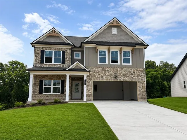 Two-story home featuring a combination exterior of stone, brick, and vertical siding