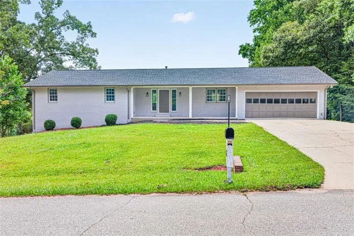 Single-story residence featuring a gray exterior, covered front entry, attached two-car garage, and a concrete driveway
