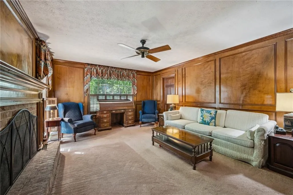 Living room featuring a brick fireplace and wood paneled walls.