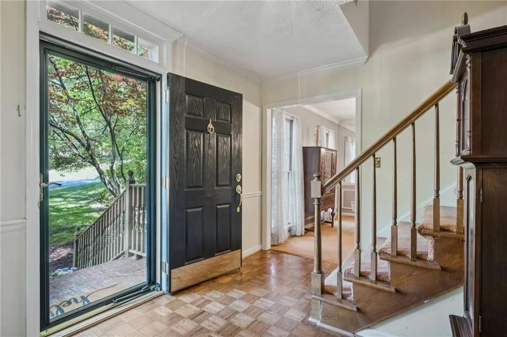 Foyer entrance featuring parquet flooring, ornamental molding, and transom window. View into dining room.