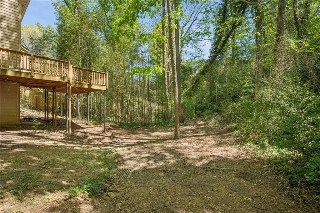 View of back yard featuring a wooden deck and small creek beyond.