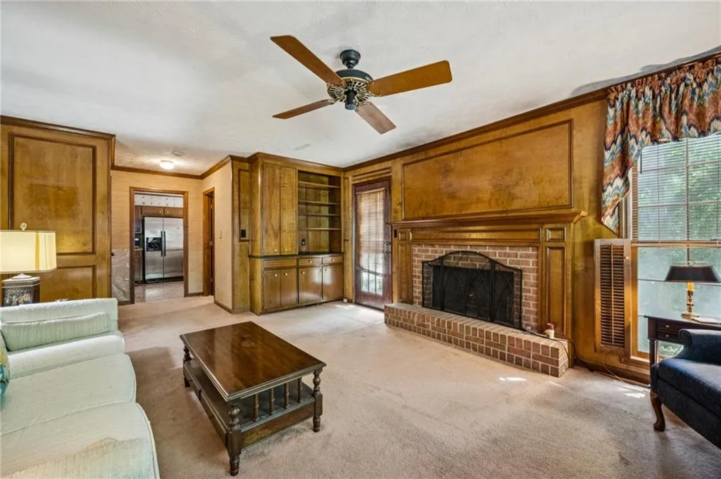 Living room with door to back deck and view into kitchen. Half bath behind shelving.