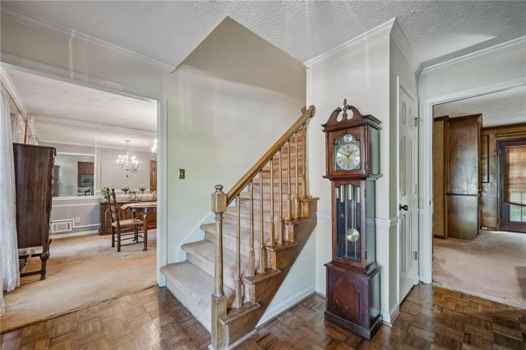 Stairs with ornamental molding, parquet flooring. View into living room on right and dining room on left. See more photos for floor plans with dimensions.