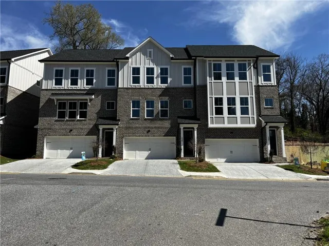 View of front of home featuring an attached garage, brick siding, driveway, and board and batten siding