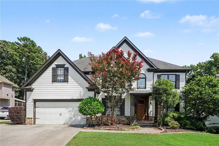 Two-story residence featuring light-colored siding, dark shutters, and a prominent front door