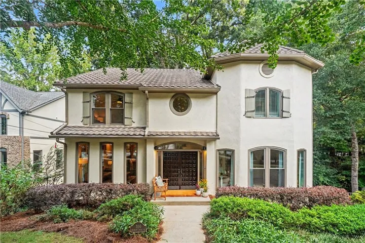 Stucco exterior with a tiled roof, arched entry, decorative front door, and varied window styles