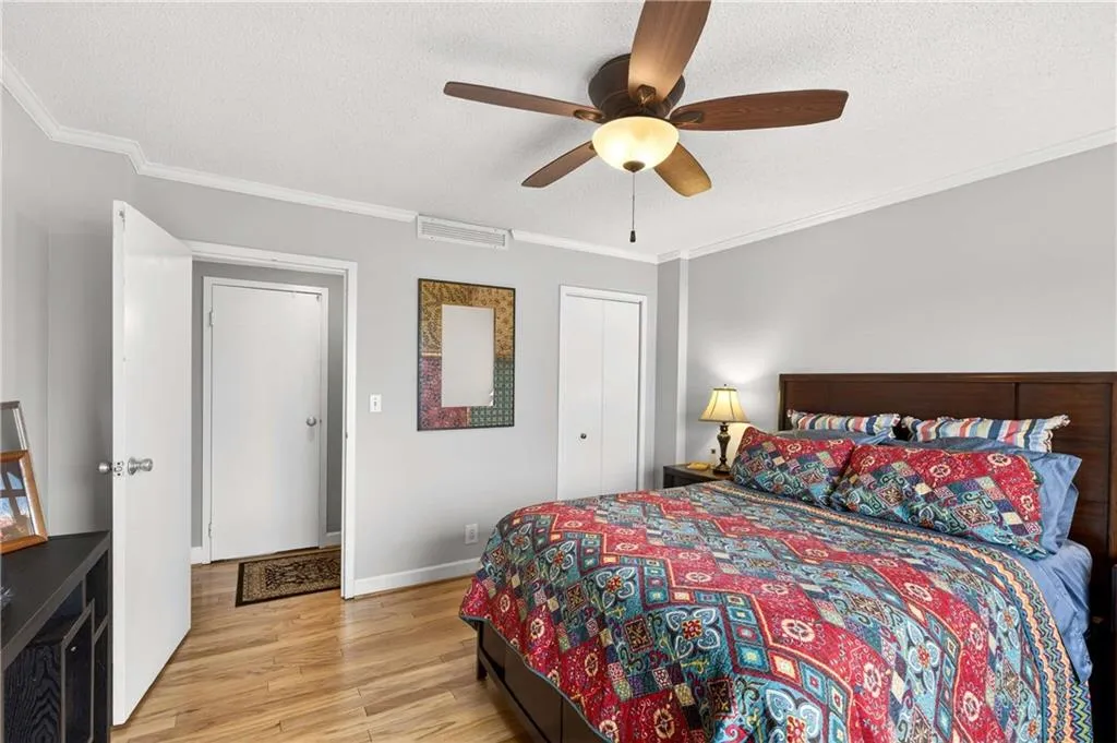 Bedroom featuring crown molding, light wood finished floors, a ceiling fan, a closet, and a textured ceiling