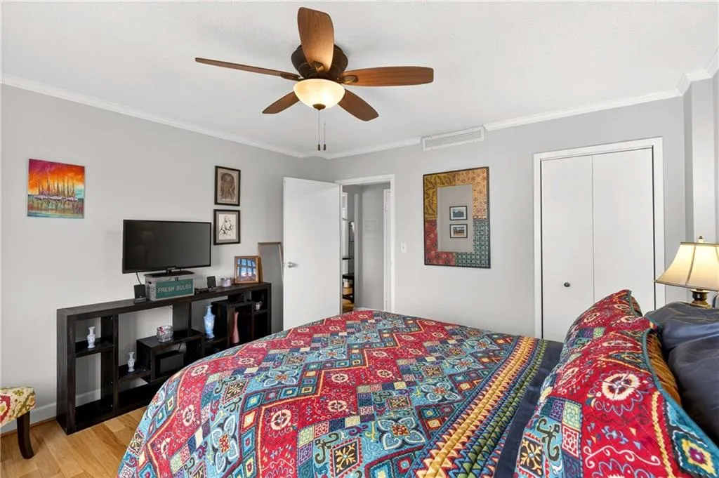 Bedroom with ornamental molding, a ceiling fan, a closet, and light wood-type flooring