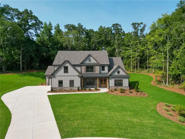 Craftsman-style home featuring a stone and shingle facade, multi-gabled roofline, and an expansive concrete driveway