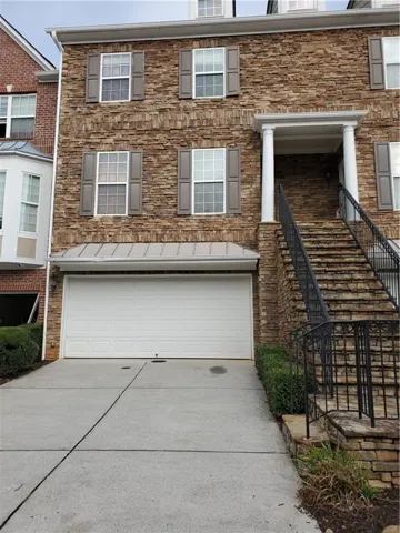 Stone facade exterior with shuttered windows, a columned entry, and an integrated two-car garage
