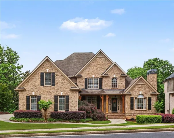 Brick exterior residence featuring multiple gables, a covered entry with wood columns, and dark window shutters