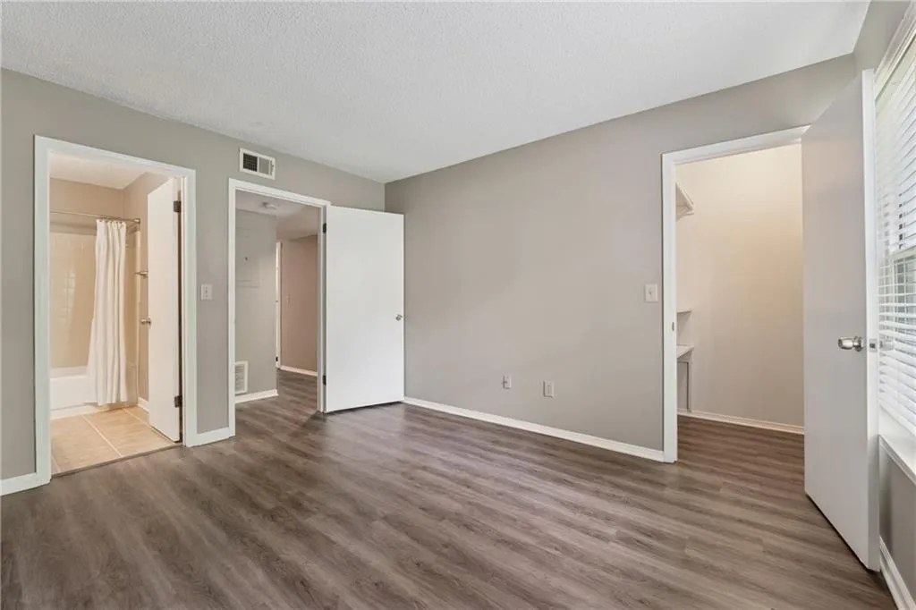 Unfurnished bedroom with wood finished floors, a spacious closet, and a textured ceiling