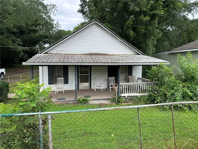 White siding exterior with a covered front porch featuring a metal roof and dark shutters