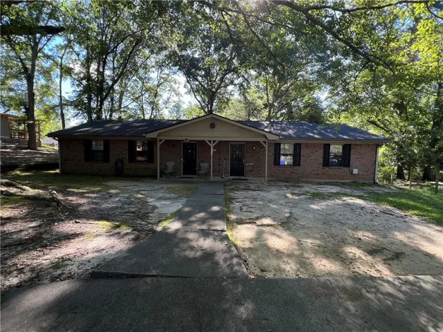 Brick exterior with covered entry, black shutters, and a driveway