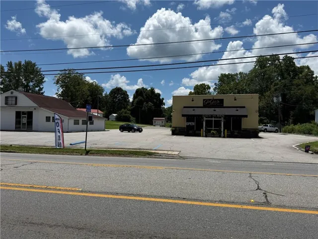 Commercial property featuring two distinct structures and a large paved parking area