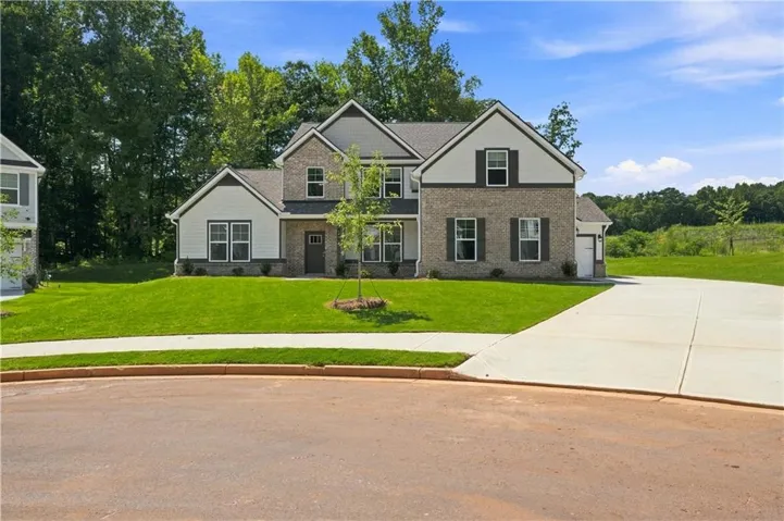 Two-story exterior with brick and siding facade, contrasting dark shutters, a front entry with sidelights, and a two-car garage