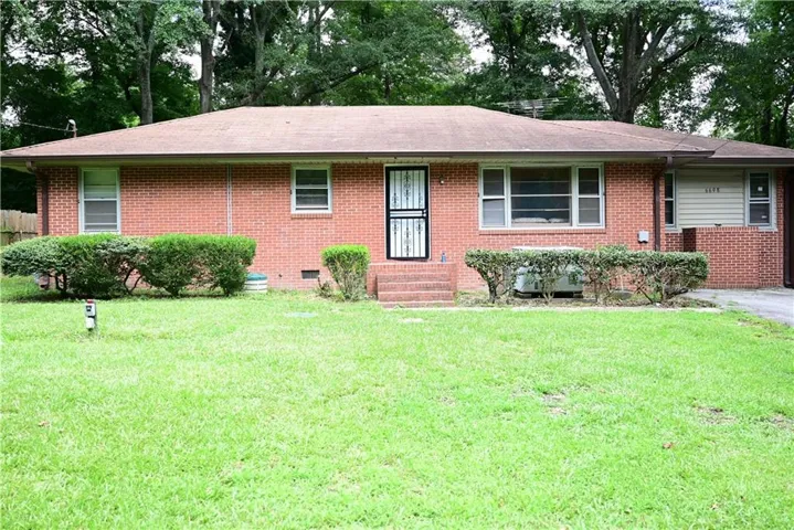 Brick exterior residence featuring a front lawn and mature trees in the background