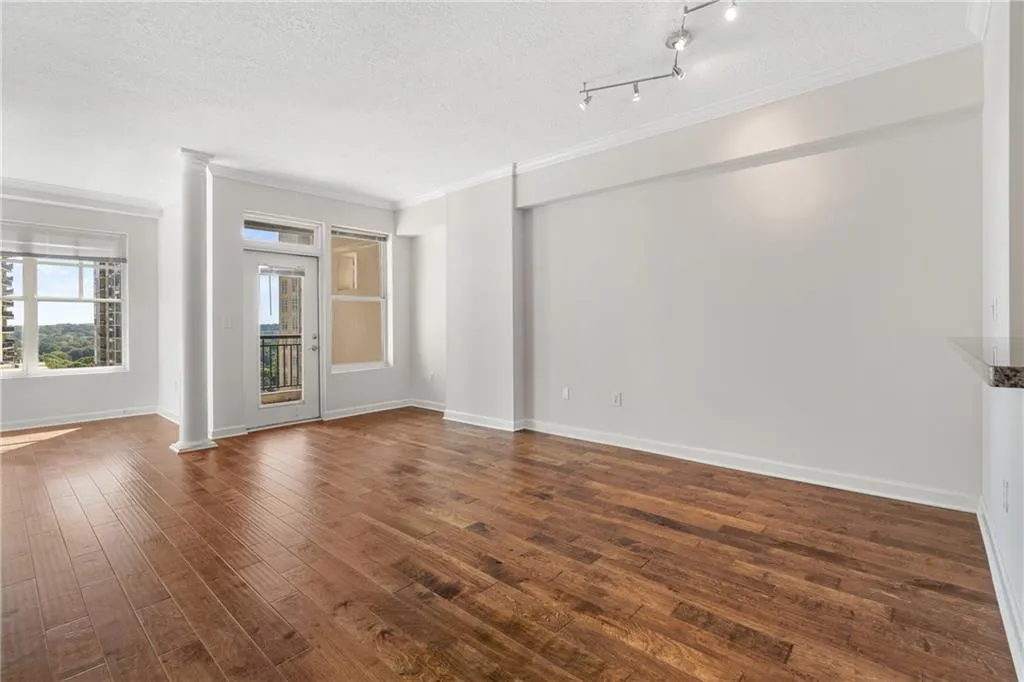 Spare room featuring ornamental molding, decorative columns, a textured ceiling, and dark wood-type flooring