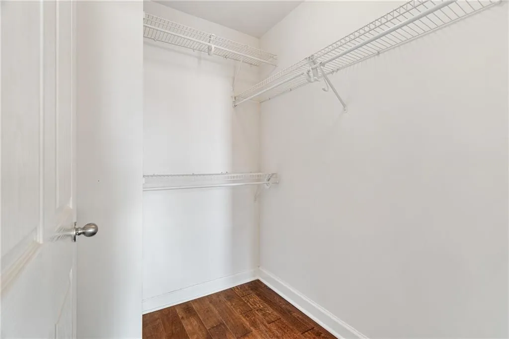 Walk in closet with dark wood-style floors