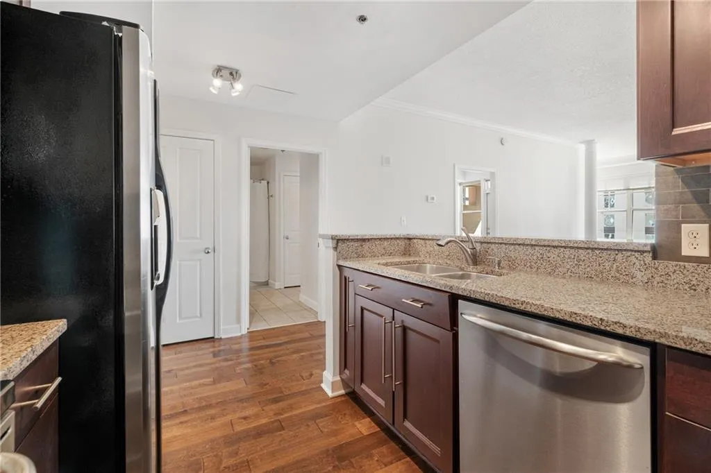 Kitchen featuring appliances with stainless steel finishes, light stone counters, dark wood finished floors, dark brown cabinetry, and a peninsula