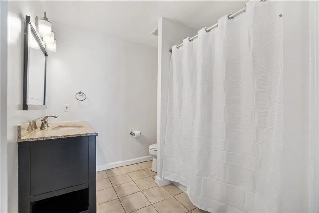 Full bathroom featuring light tile patterned floors, vanity, and a shower with curtain