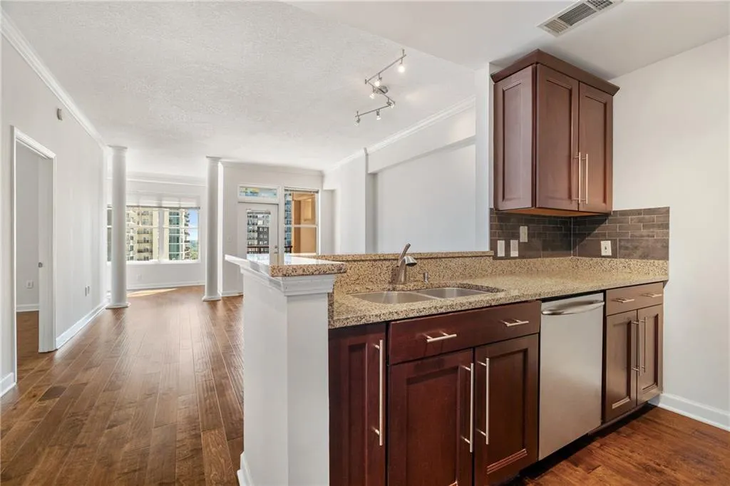 Kitchen with decorative columns, crown molding, light stone countertops, dishwasher, and tasteful backsplash