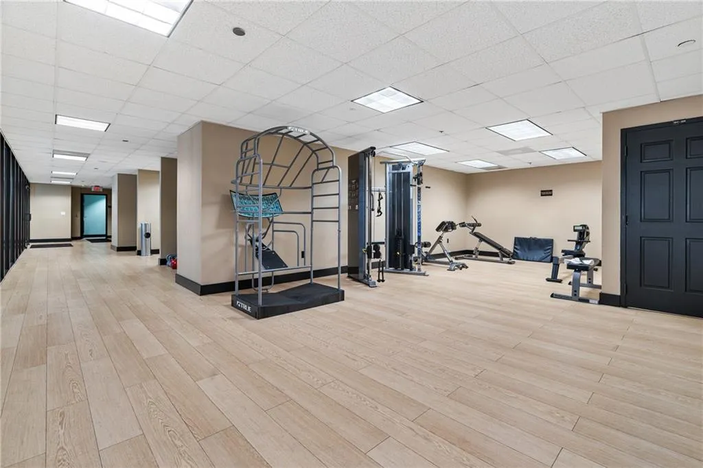 Gym with light wood finished floors and a paneled ceiling